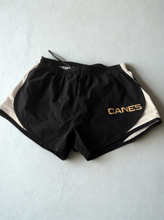 Black shorts with 'CANES' logo on a light gray surface