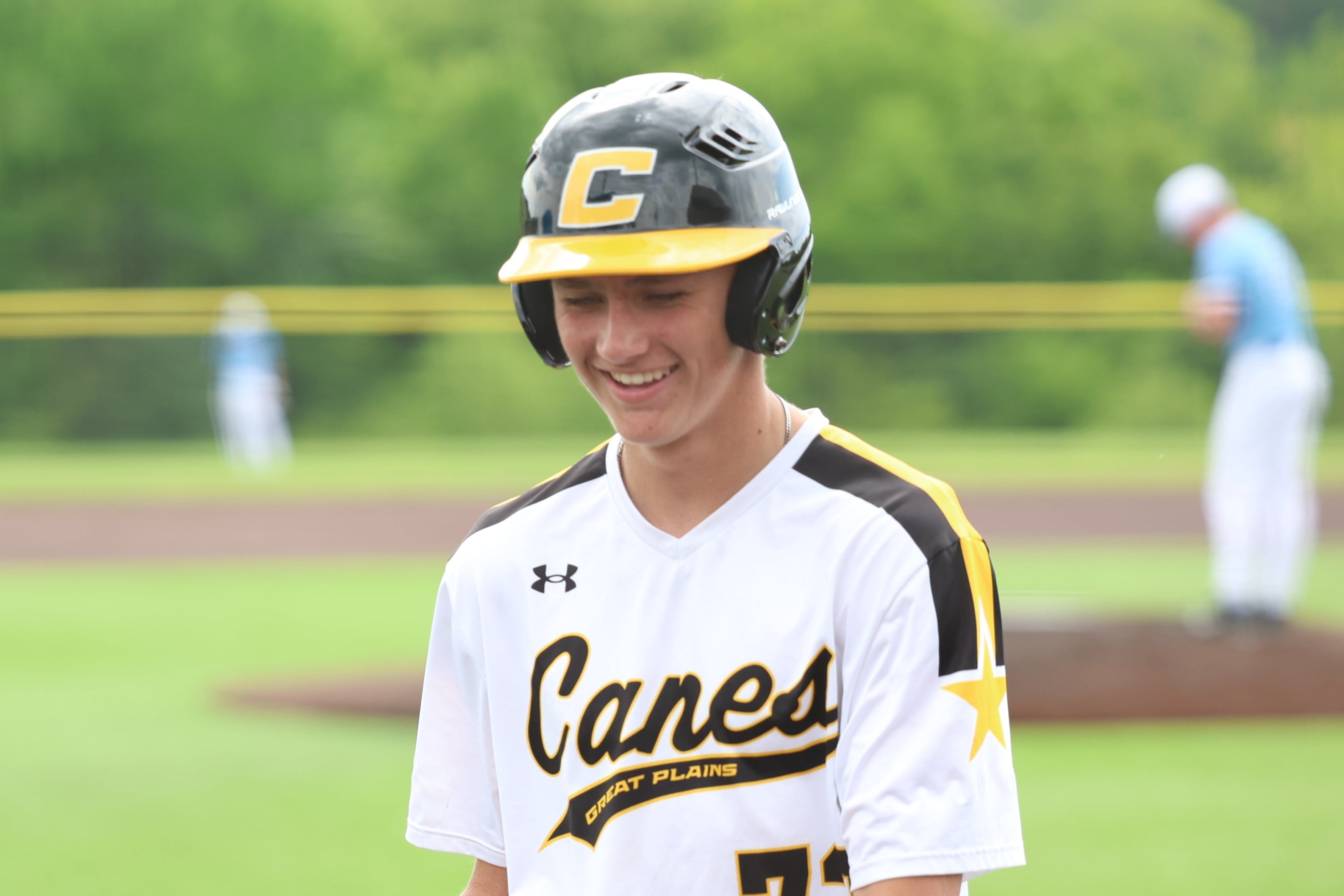 Baseball player in a 'Canes' uniform holding a bat on a baseball field.