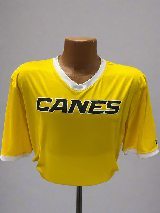 Yellow sports jersey with 'Canes' branding on a mannequin against a display background.