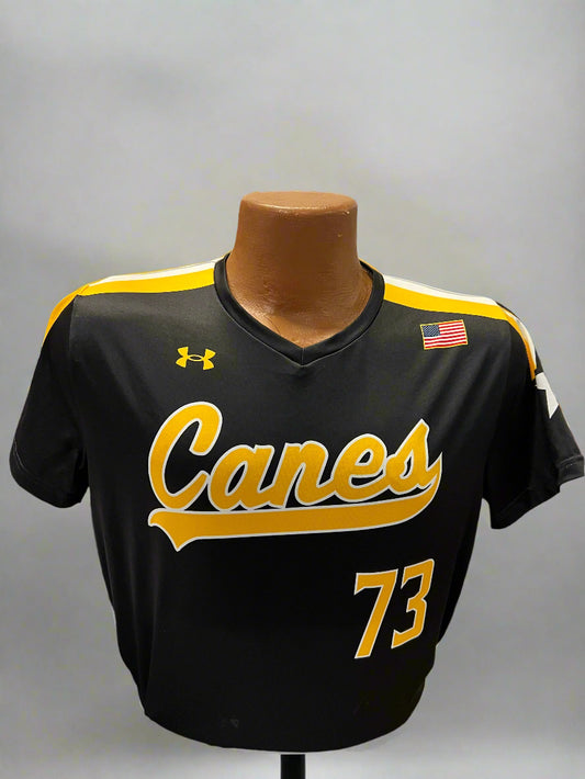 Black sports jersey with yellow text and number on a mannequin, displayed against a background of similar jerseys.