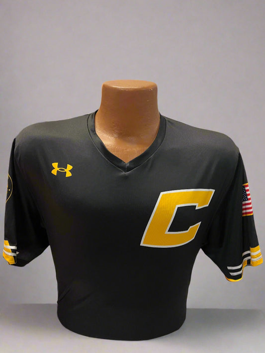 Black sports jacket with yellow logo on a mannequin against a display of similar jackets.