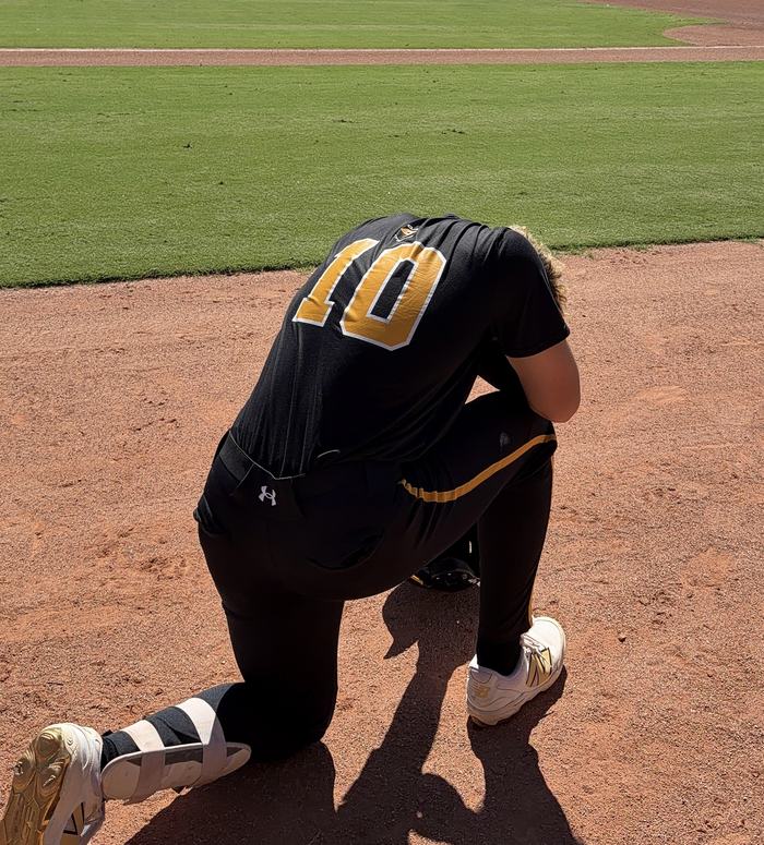 Canes player number 10 in the black uniform, kneeling on the infield
